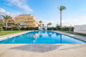 a swimming pool in front of a building with palm trees at Penthouse studio with sea views in La Cala de Mijas