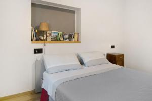 a bedroom with a white bed with two pillows at Ca Del Tita in Capo di Ponte