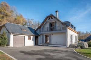 a white house with a garage on a driveway at Maison Vacances Vue Montagnes in Arras-en-Lavedan