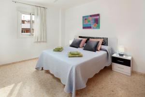 a white bedroom with a bed with two green towels on it at Apartamento Sugar Factory in Torre del Mar +21 photos