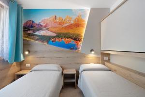 two beds in a room with a painting on the wall at Night and day 4 in Predazzo