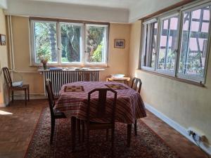 a dining room with a table and chairs and windows at Maison de Jeanne in Eschau