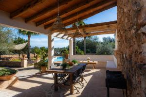 a patio with a wooden table and a stone wall at Finca Ca S'Hereu Mas in Campos