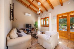 a living room with two white chairs and a tv at Finca Ca S'Hereu Mas in Campos