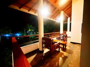 a porch with two chairs and a table on a balcony at night at Anu villa Bentota in Bentota +24 photos