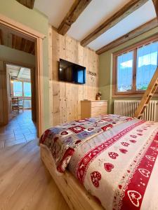 a bedroom with a bed with a red and white comforter at Casa Clus Bormio apartments 3 in Valdisotto