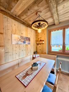 a dining room with a wooden table and a chandelier at Casa Clus Bormio apartments 3 in Valdisotto