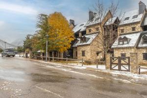 a snowy street in front of a stone house at Apartamento La Mainera in Espot