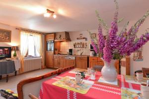 a kitchen with a table with a vase of purple flowers at Les Hirondelles in Orbey