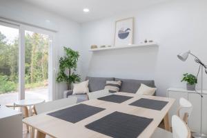 a white living room with a table and a couch at Aptos Ría San Cosme Aurora in Bendimón +25 photos