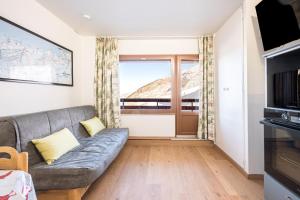 a living room with a couch and a large window at Appartement Les Menuires in Les Menuires