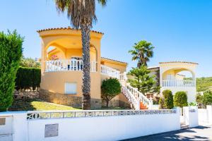 a large yellow house with a white fence and palm trees at Villa Individual Peñíscola in Peniscola