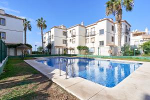 a swimming pool in front of a building with palm trees at La Mejor in Torrox