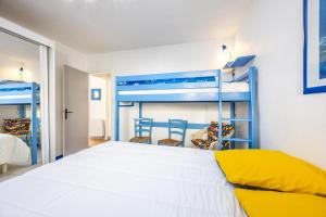 a bedroom with two bunk beds and two chairs at Maison vacances La Terrière in La Tranche-sur-Mer