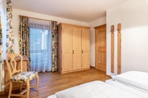 a bedroom with a bed and a chair and a window at Cesa Valeria App Sonia in Ortisei