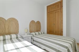 a bedroom with two beds and a wooden door at Apartamento Perez Zara 7 in Conil de la Frontera