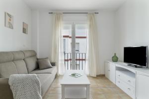 a living room with a couch and a tv at Apartamento Perez Zara 7 in Conil de la Frontera