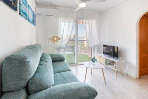 a living room with a green couch and a television at Mistral Apartment La Manga in San Javier