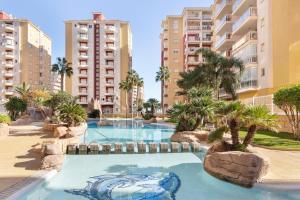 a swimming pool in a resort with palm trees and buildings at Mistral Apartment La Manga in San Javier