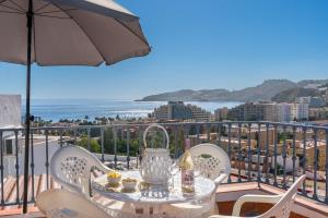 a table and chairs on a balcony with an umbrella at Casa Carmen in Almuñécar