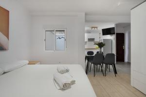 a white bedroom with a bed and a dining room at Loft Guanapay 2 in Los Cristianos