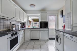 a kitchen with white cabinets and a dishwasher at Bungalow vor Sylt in Klanxbüll +11 photos