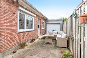 a patio with a couch and a table on a brick building at Bungalow vor Sylt in Klanxbüll