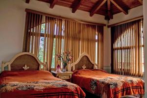 two beds in a room with windows and curtains at Cabañas Monte Escondido in Mazamitla