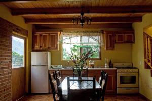 a kitchen with a table and a white refrigerator at Cabañas Monte Escondido in Mazamitla