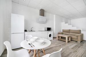 a white kitchen with a white table and chairs at Apartamento Venus 2 in Conil de la Frontera +15 photos