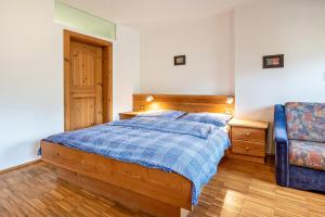 a bedroom with a bed with a blue blanket and a chair at Lindenhof Apt 2 in Vandoies