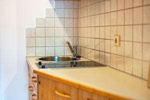 a kitchen with a sink and tiled walls at Lindenhof Apt 2 in Vandoies +10 photos