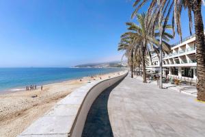 a walkway along a beach with palm trees and the ocean at Casa Vale do Paraíso in Sesimbra