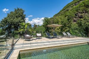 a pool with chairs and an umbrella next to a mountain at Videre Lodge Wasserfall in Gargazzone