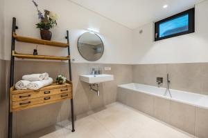 a bathroom with a sink and a tub and a mirror at Videre Lodge Wasserfall in Gargazzone