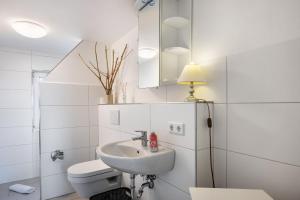 a white bathroom with a sink and a toilet at Huus achtern Diek in Nordstrand +21 photos