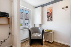 a chair in a room with a desk and a window at Huus achtern Diek in Nordstrand