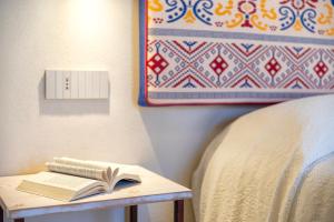 a book on a table next to a bed at Dimora Sella Rooms in Alghero