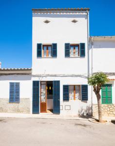 a white building with blue shutters and a tree at Sa Caseta in Felanitx