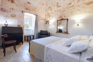 a bedroom with a bed and a chair and a mirror at Trulli i Cedri, Monopoli in Monopoli