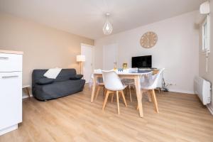 a living room with a dining room table and a couch at L'Optimist, parking, proche plages in Arzon