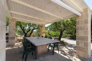 a patio with a wooden pergola with a table and chairs at Trulli i Cedri, Monopoli in Monopoli