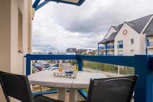 a table and chairs on a balcony with a view of a parking lot at L'Optimist, parking, proche plages in Arzon