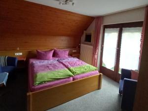 a bedroom with a bed with purple and green sheets at Ferienwohnung Faller in Elzach