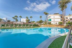 a large swimming pool with palm trees and buildings at Estudio Yumbo Playa in San Bartolomé