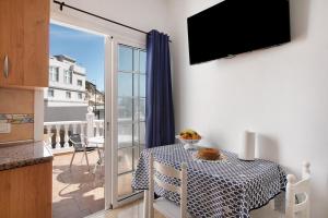 a room with a table and a balcony with a television at Atico Las Arenas in Arico