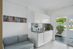 a white kitchen with a couch and a microwave at Estudio Yumbo Playa in San Bartolomé