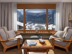 a living room with two chairs and a table and a window at Apartment SnowKaya Grindelwald by Interhome in Grindelwald
