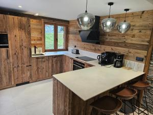 a kitchen with wooden walls and a counter with stools at Chalet Azureva Sauna, Jacuzzi, Spa in Levassaix +23 photos