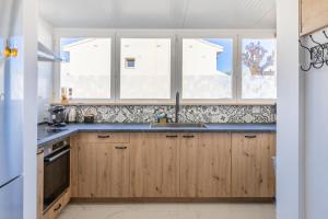a kitchen with wooden cabinets and a sink and windows at Sol y Sombra in El Campello